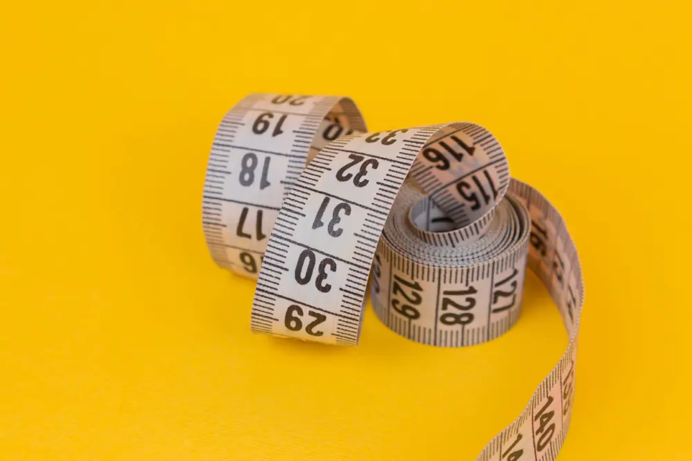 The image symbolically depicts a tape measure, symbolizing the measurement of the patient's silhouette during the Gastric Sleeve procedure. Learn more about this procedure and its benefits in our dedicated article.