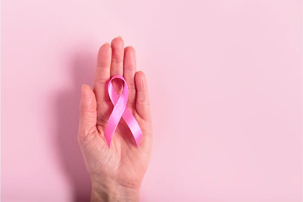 The image depicts a stethoscope and a pink ribbon, symbols associated with mastectomy and its assessment.