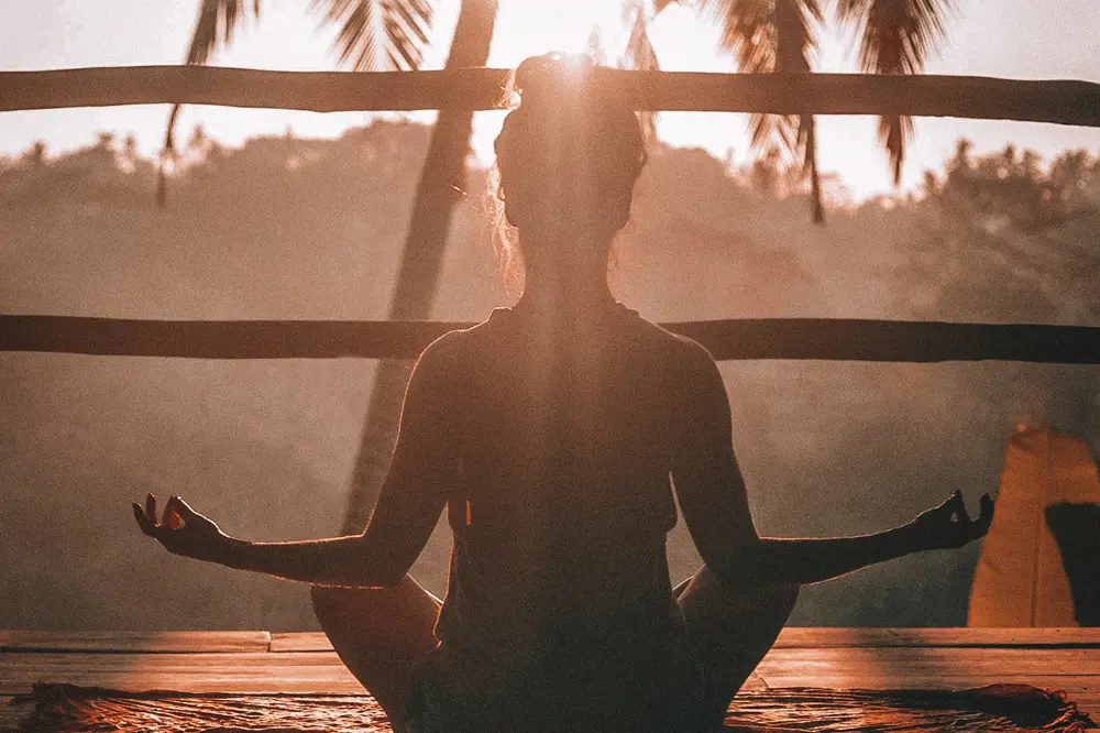 The image shows the relaxed silhouette of a woman practicing yoga, sitting quietly on her bottom and expressing her lack of concern about hemorrhoids. Learn more about how to prevent hemorrhoids and the benefits of relaxation activities in our specialized article.