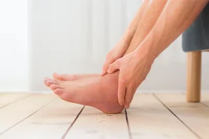 Representative image of May Thurner syndrome. Image of a man's hands holding his left leg, which is swollen due to pain.